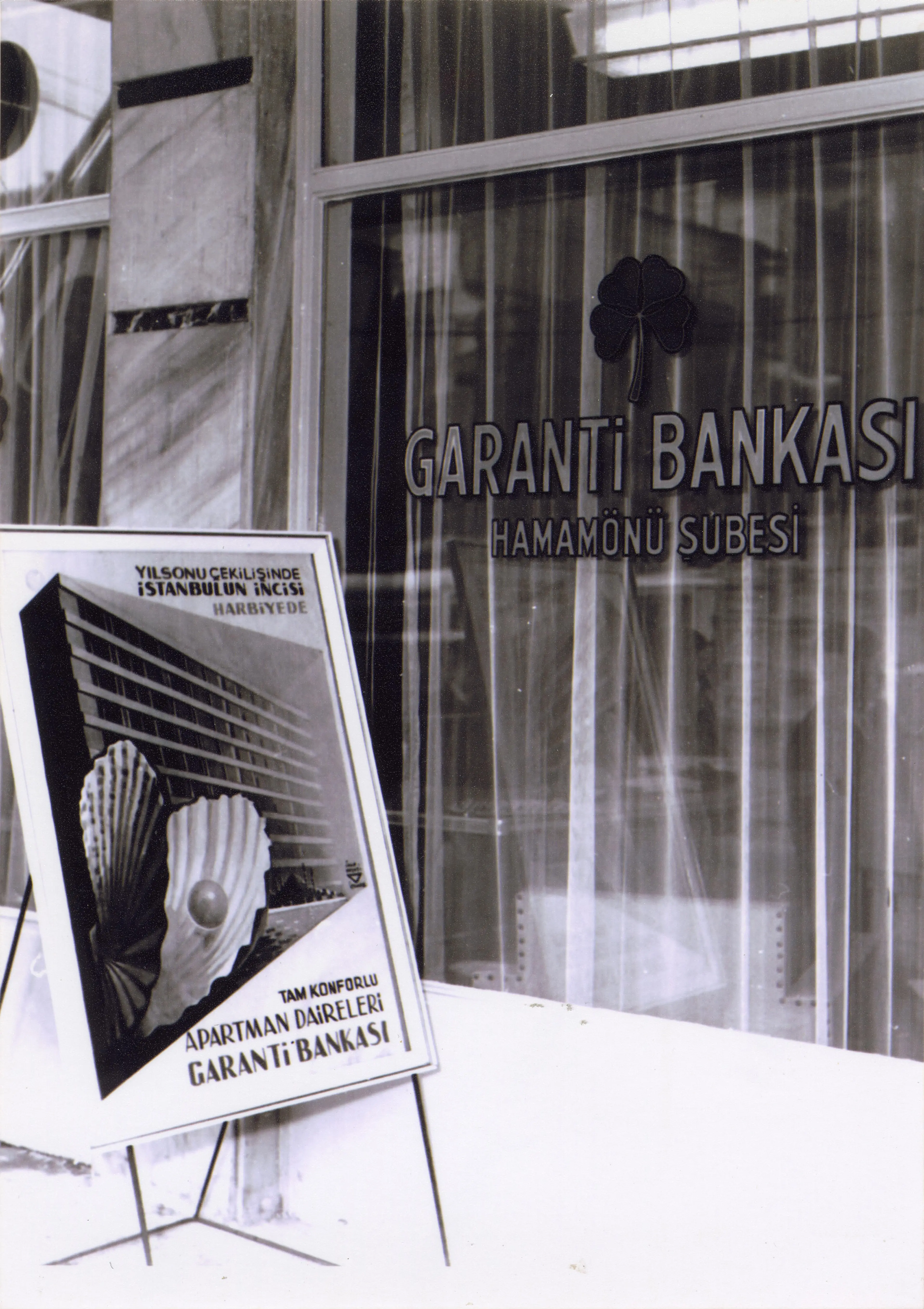 Garanti Bankası Hamamönü Şubesi (Ankara) ve önünde İhap Hulusi Görey’in tasarladığı apartman çekilişi afişi, 1950’ler Salt Araştırma, Garanti BBVA Arşivi