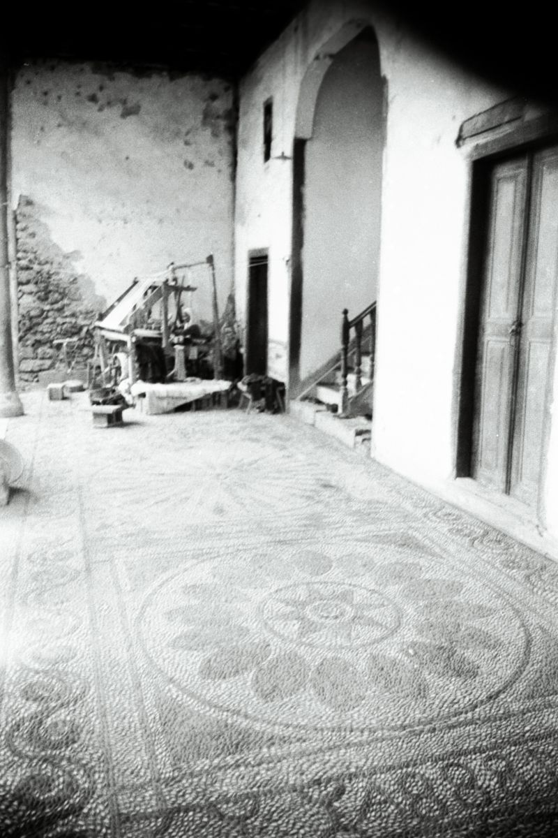 Gorsel12 Tcbh201703201 Dokuma tezgâhı ile mozaik döşemeli taşlık ilişkisine odaklanan bir fotoğraf (Cengiz Bektaş’ın Antalya gezisi sırasında çektiği fotoğraflar; 35 mm, siyah beyaz negatif film)<br />
Salt Araştırma, Cengiz Bektaş Arşivi <br />
<i>Mimarlık</i> dergisinin 154. sayısında Bektaş, mozaik döşemeli taşlığı Mavi Anadolucuların da sıklıkla dillendirdiği, halk sanatında kültürel devamlılık tezi ile yorumlayacaktır: “Yüz elli yıllık Antalya evinin taşlığında, küçük çakıllarla yapılan döşemeyi, binlerce yıl öncesinin yerleşmesinde bulduğumda, binlerce yıldır sürüp gelen bir eli, bir kültürü duydum içimde. Bu kültürü, ulusal şu-bu diye tanımlamaya kalkışanlara; şu Yunan, şu Roma, şu şu, bu bu diye duvarlarla bölmeye kalkışanlara azıcık şaşarak, azıcık kuşkuyla baktım.” (s. 6) 